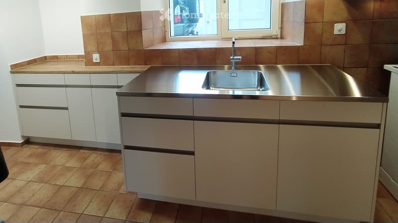 Modern kitchen with stainless steel sink, wooden cabinets, and tiled backsplash.