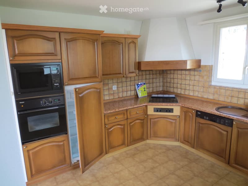 Well-lit kitchen with wooden cabinets, granite countertops, and stainless steel appliances including an oven, microwave, and dishwasher. A window provides natural light.