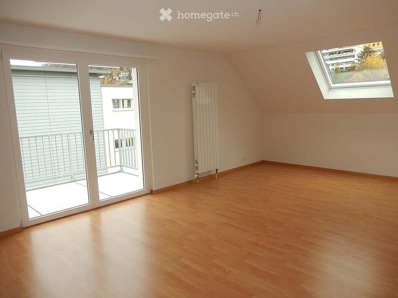 Empty room with wooden flooring, white walls, large sliding glass door leading to a balcony, radiator, and skylight window.