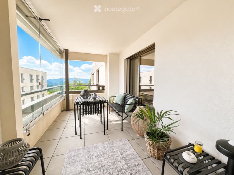 Balcony with modern furniture, including a black table, chairs, a bench, vases, a rug, and potted plants, overlooking a scenic view.