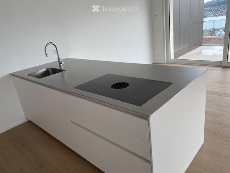modern kitchen with open floor plan, stainless steel sink, black stovetop, white cabinetry, wooden floor