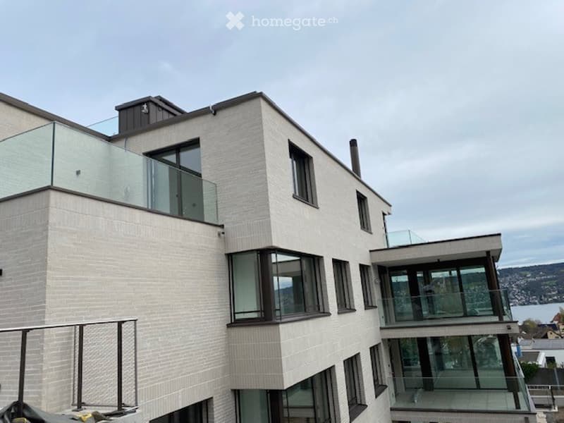 Multi-story building with glass balconies, brick facade, modern design