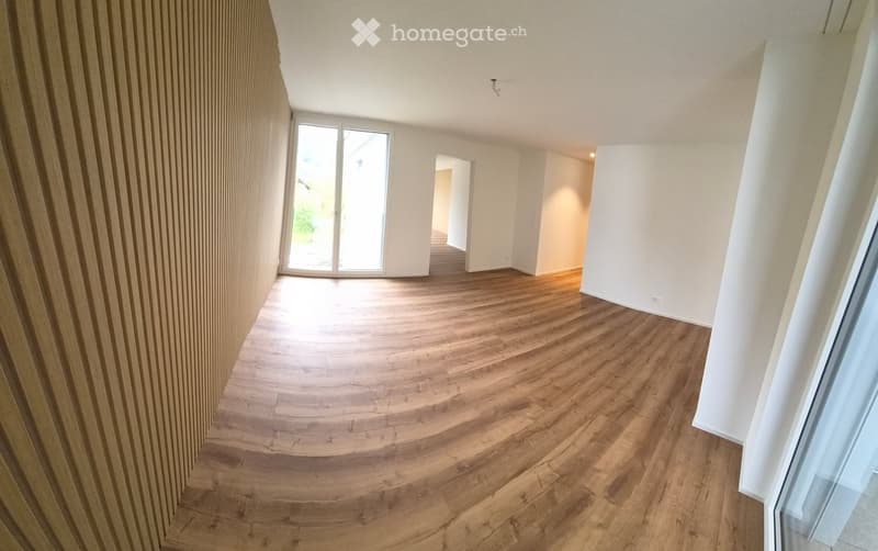 Empty room with wooden flooring, white walls, and large windows allowing natural light to enter. The space is clean and unfurnished, with no visible furniture or decorations.