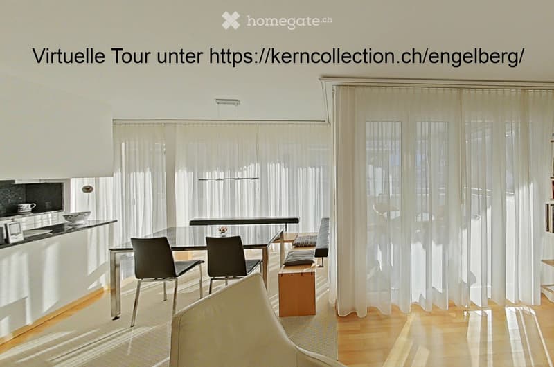 Bright, modern living and dining area with large windows covered by sheer curtains, a white sofa, a glass dining table with chairs, a small wooden stool, and a sleek kitchen counter with a cup and bowl.