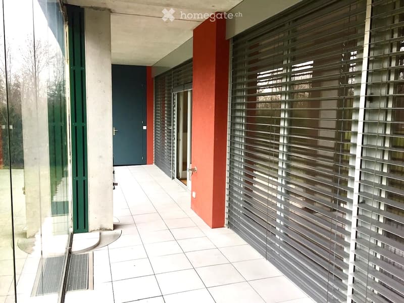 Modern hallway with white tiled floor, glass door, grey door, and red accent wall.