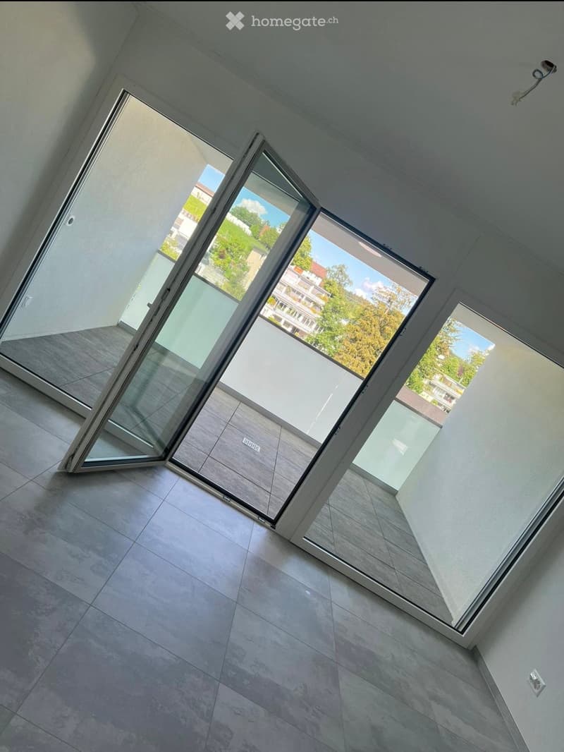 Empty room with large sliding glass doors leading to a balcony, tiled floor, and white walls.