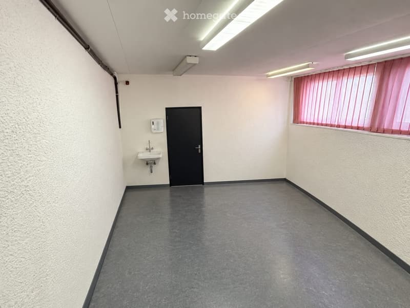 Empty room with grey concrete floor, white walls, a small sink, and a window with pink curtains.
