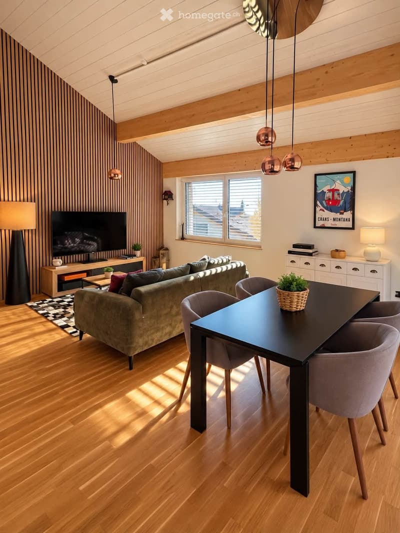 Modern living and dining area with wooden flooring, a green sofa, a black dining table with chairs, a television on a stand, and decorative lamps.