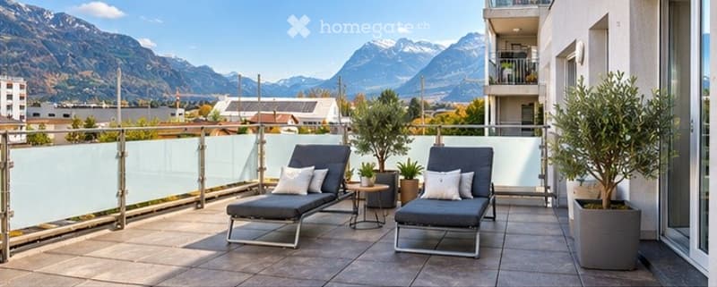 Balcony with lounge chairs, small table, potted plants, and a scenic mountain view.