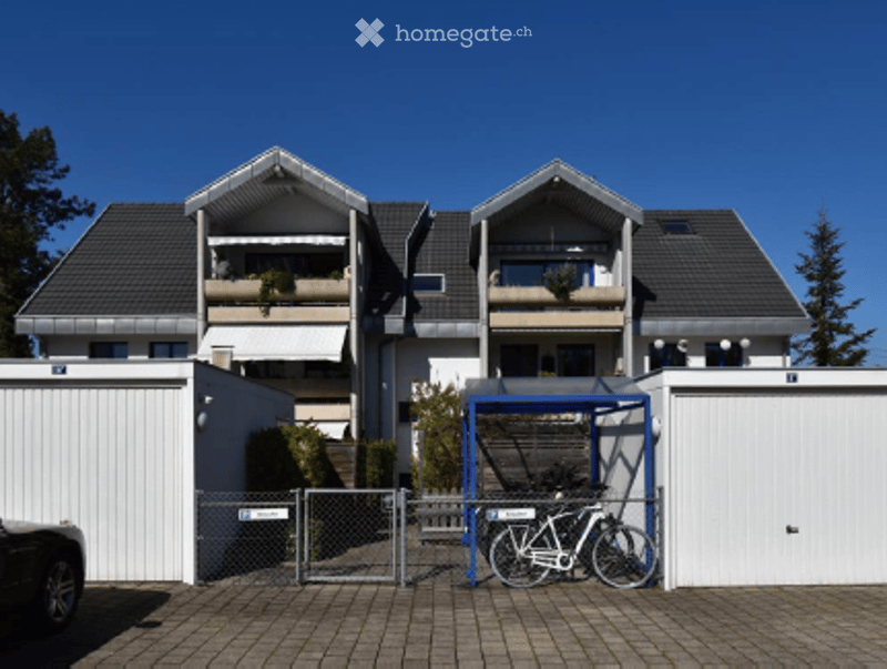 Modern two-story apartment building with balconies, garage, and parking area.