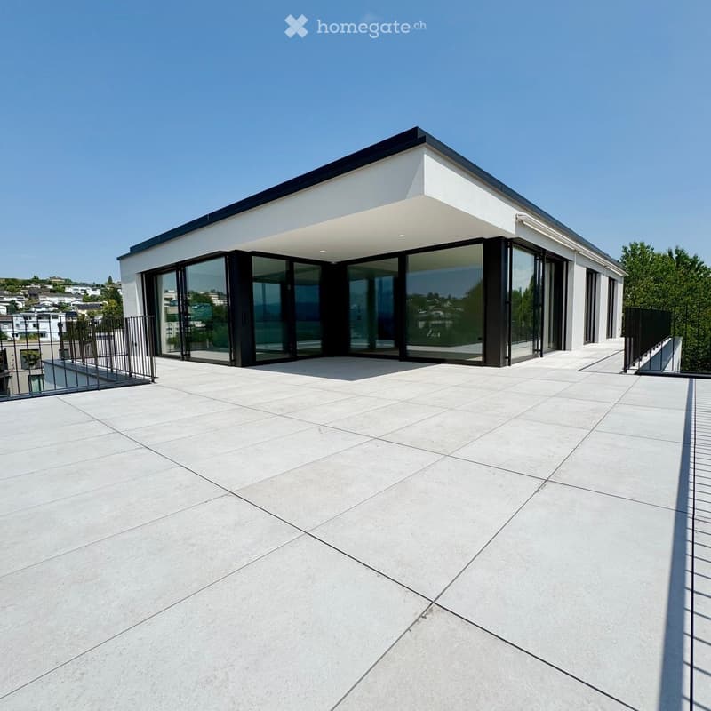 Modern rooftop terrace with large glass sliding doors, white tiled floor, and metal railings.