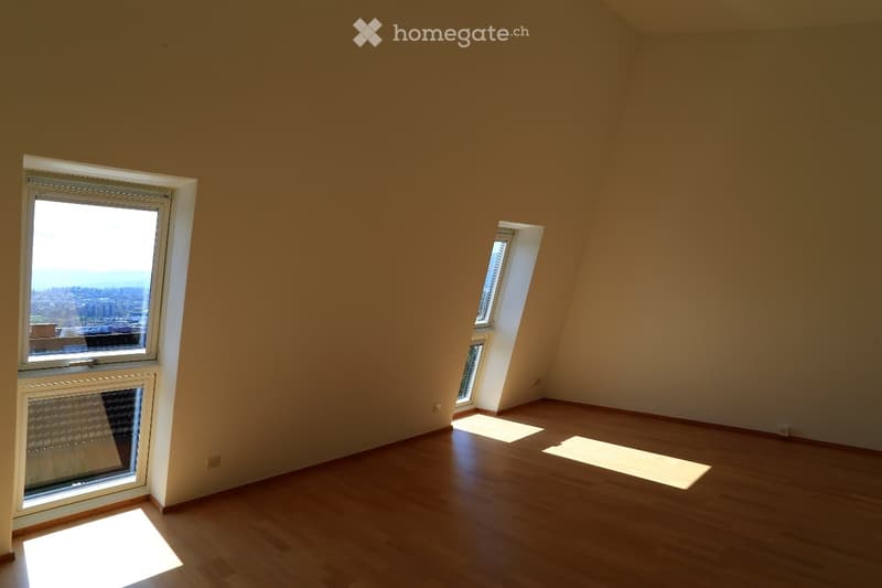 Empty room with wooden flooring and large windows offering a city view. No furniture or equipment present.