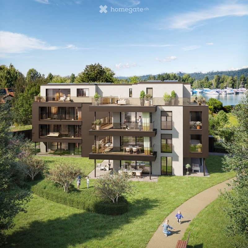 Modern two-story house with large windows, balconies, and outdoor seating areas, surrounded by a well-maintained garden and located near a waterfront with boats.