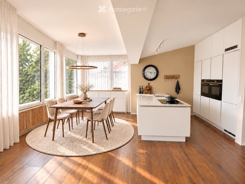 Modern kitchen with white cabinets, wooden dining table, six chairs, and a kitchen island with sink and oven. Large windows with sheer curtains, pendant light, and a round rug.