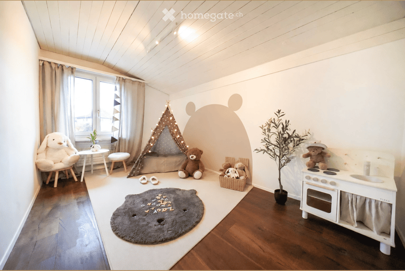 Cozy children's room with wooden flooring, a play tent, a small table, a toy stove, and plush toys.