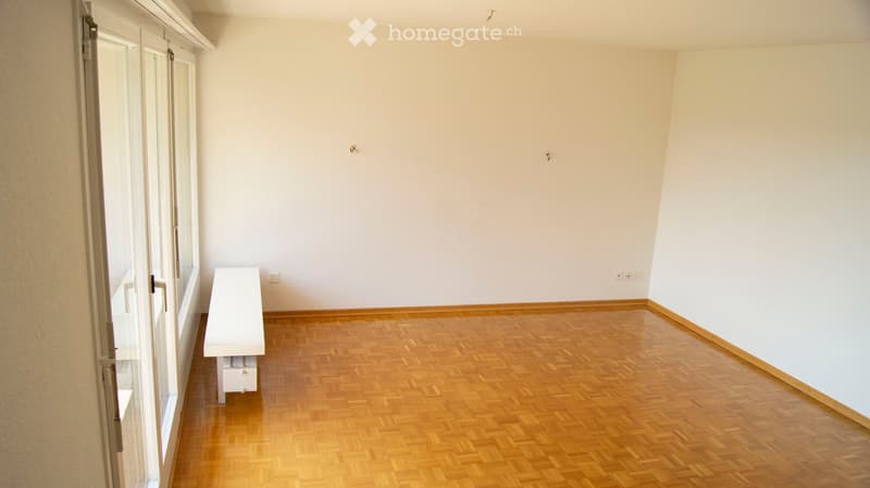 Empty room with wooden flooring, white walls, and large windows. No furniture or equipment present.