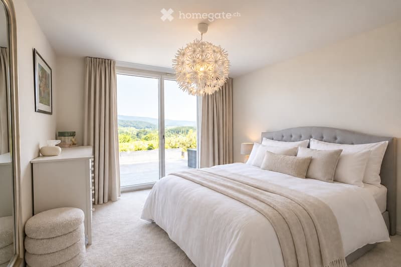 Bright bedroom with a large bed, nightstand, and a view of the landscape through large windows.