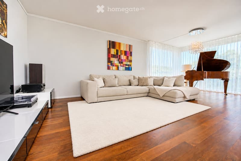 Modern living room with a large sectional sofa, a grand piano, a white shag rug, a sleek TV stand, and large windows with sheer curtains.