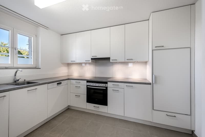 Modern kitchen with white cabinets, stainless steel appliances, and a grey countertop.