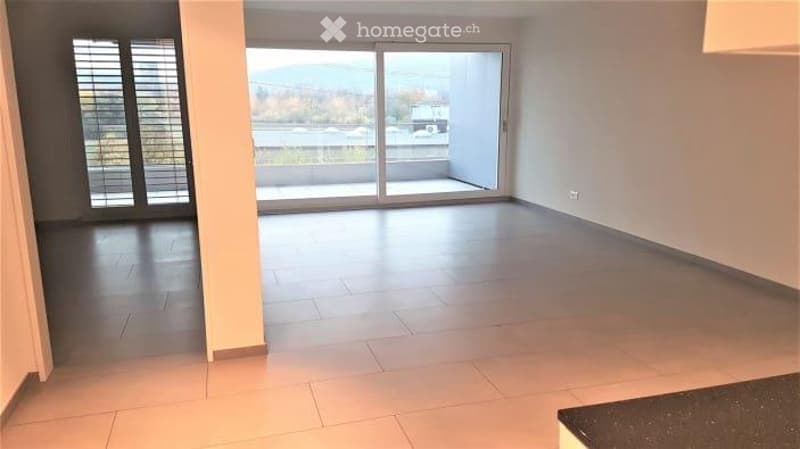 Empty room with large sliding glass doors leading to a balcony, tiled floor, and neutral-colored walls.
