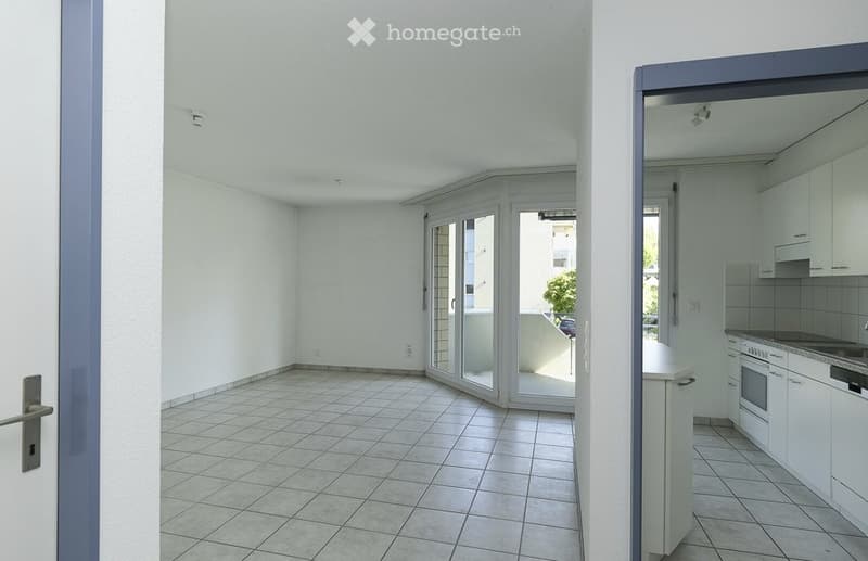 Empty room with tiled floor, white walls, and sliding glass doors leading to a balcony.