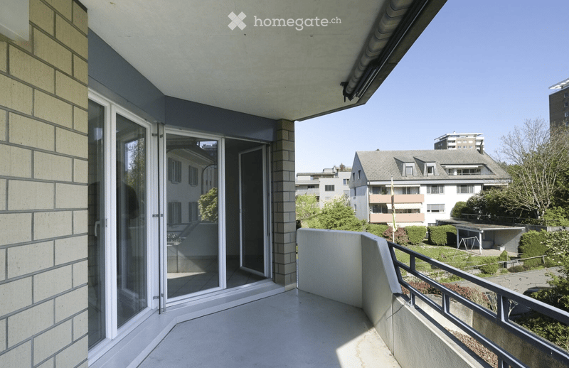 Balcony with glass sliding doors, metal railing, and a view of the surrounding residential area.