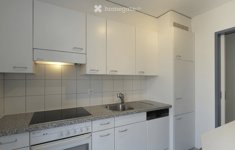 Modern kitchen with white cabinets, granite countertop, stainless steel sink, oven, and dishwasher.