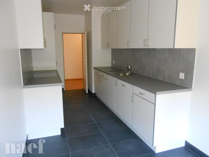 Modern kitchen with white cabinets, dark countertops, and a stainless steel sink.