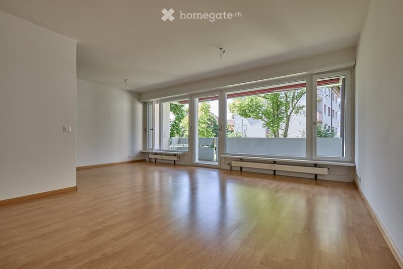 Empty room with wooden flooring, large windows, and radiators along the walls.