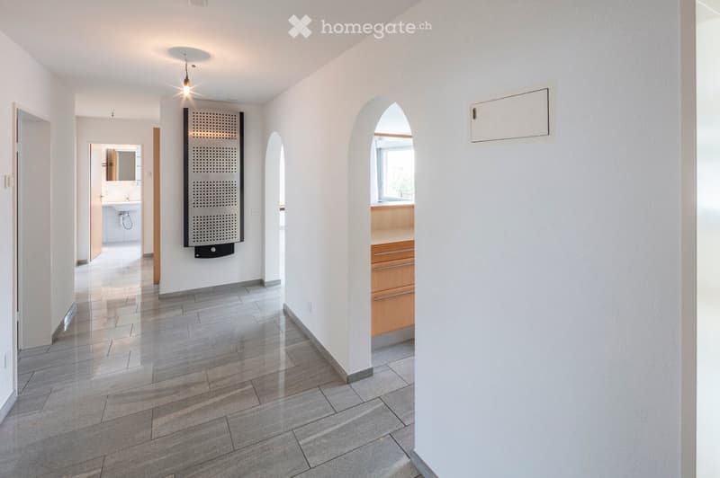 Modern hallway with white walls, tiled floor, recessed lighting, and arched doorways leading to other rooms.