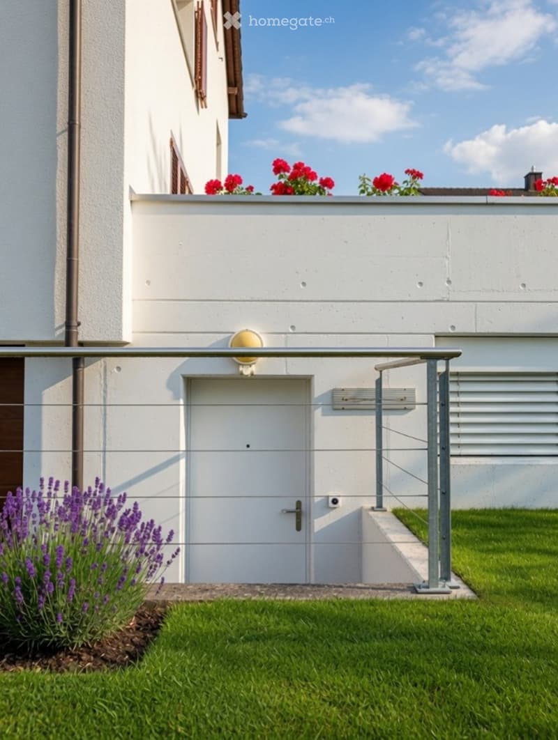 Modern white building with a raised entrance, glass railing, and flower boxes on the roof. The entrance features a white door with a small window above it, and the surrounding area includes a well-maintained lawn and lavender plants.