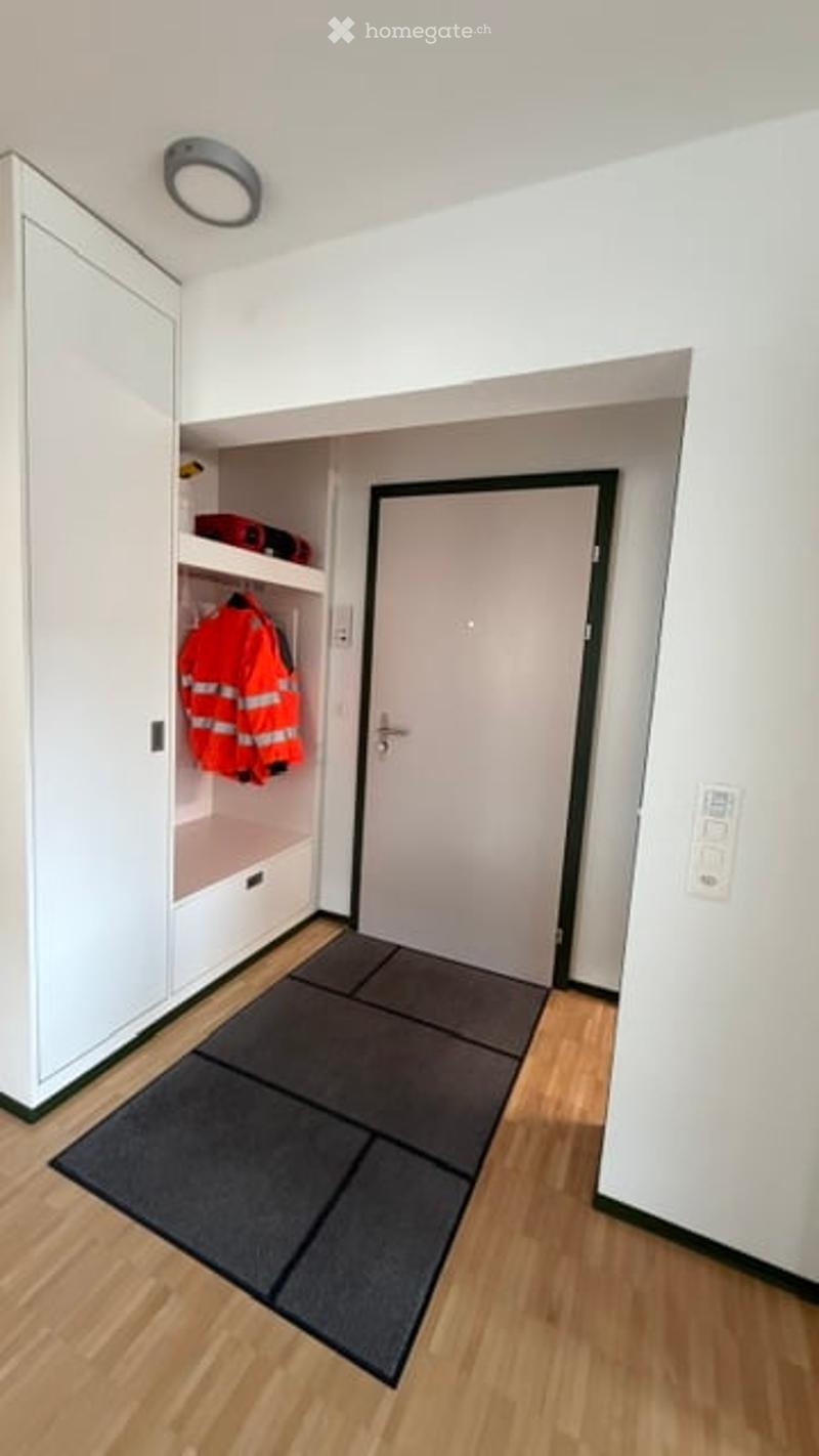 Empty room with wooden flooring, white walls, built-in closet with shelves, and a closed door.