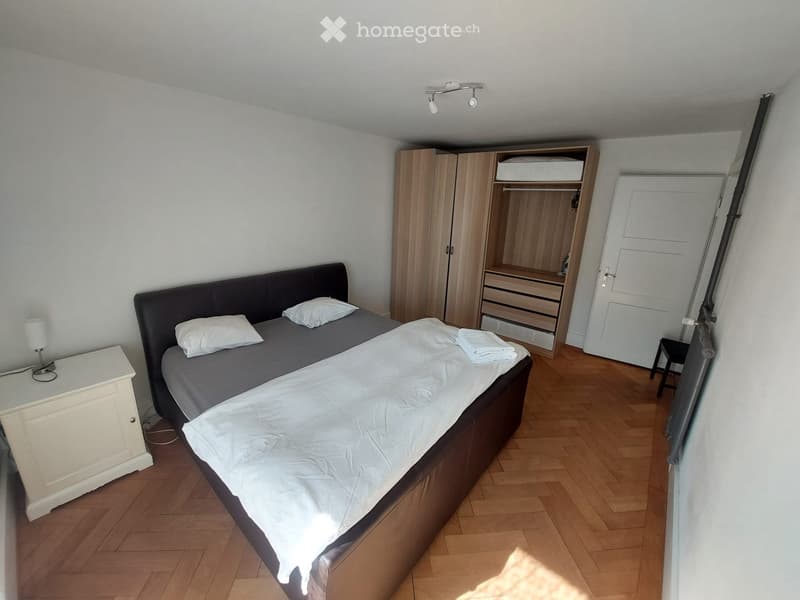 Cozy bedroom with a double bed, nightstand, wardrobe, and a small lamp on the nightstand.