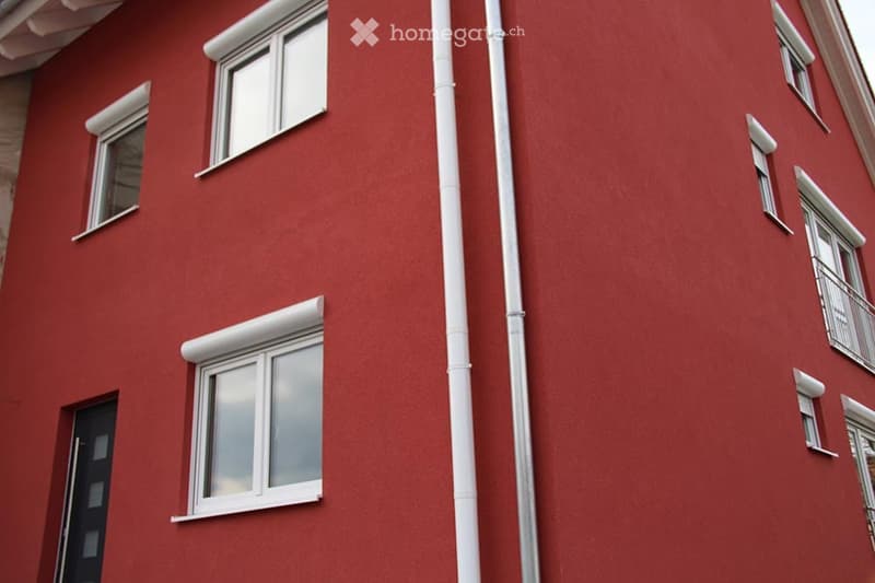 Red brick building with white-framed windows and a vertical white pipe running down the center.