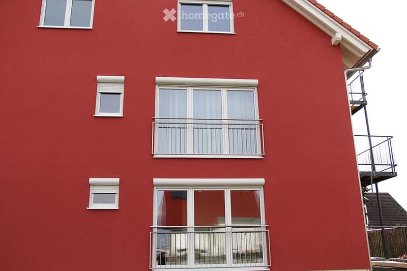 Red brick building with multiple windows and balconies.