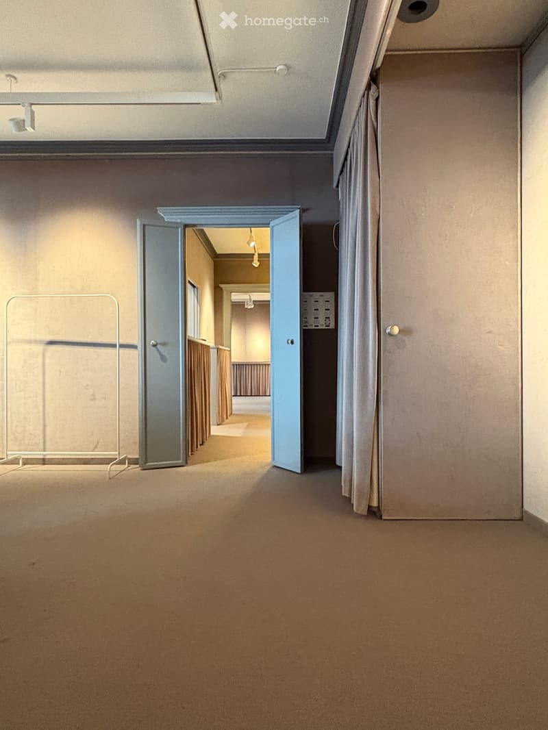 Empty hallway with beige carpet, light-colored walls, and an open door leading to another room.