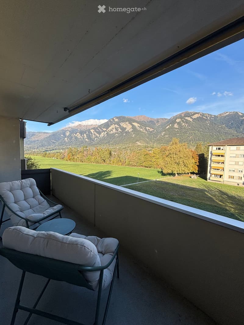 Balcony with a scenic mountain view, featuring two chairs and a small table.