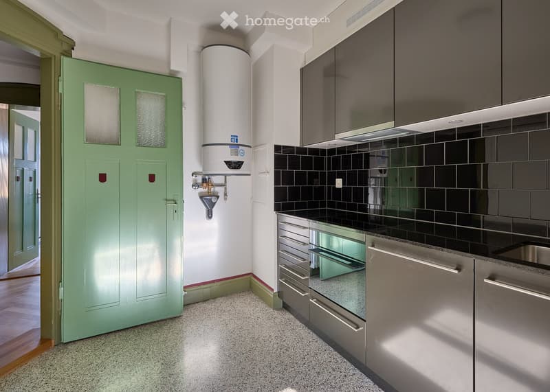 Modern kitchen with dark grey cabinets, stainless steel appliances, and a water heater in the corner.