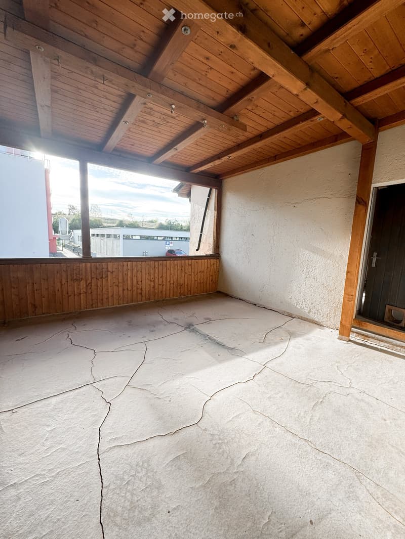 Empty room with wooden ceiling beams, exposed wooden walls, and cracked concrete floor. No furniture or equipment present.