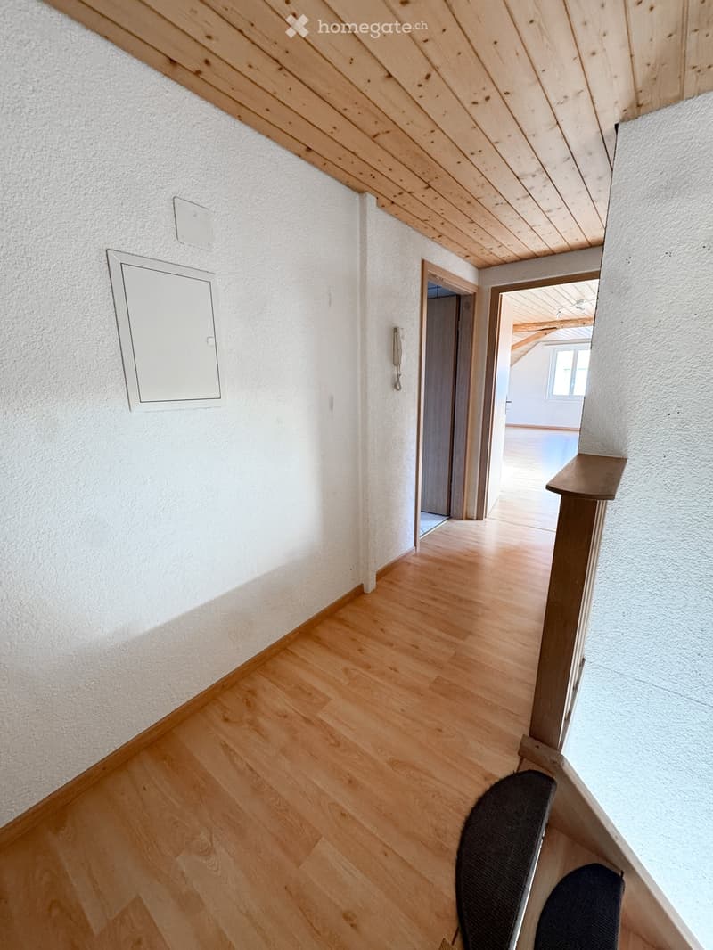 Empty hallway with wooden flooring, white walls, and exposed wooden beams on the ceiling. Two doors lead to adjacent rooms.