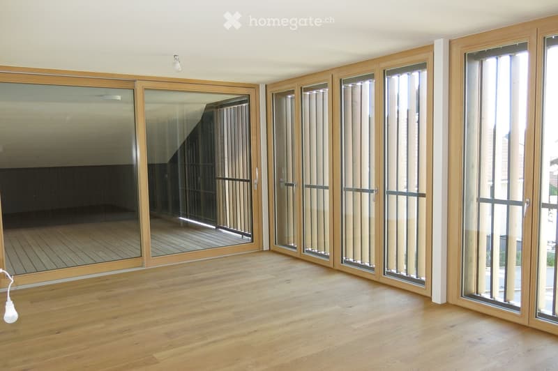 Empty room with wooden flooring and large sliding glass doors leading to a balcony or outdoor area.