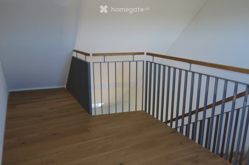 Modern staircase with wooden steps and metal railings, featuring a sleek design and bright lighting.
