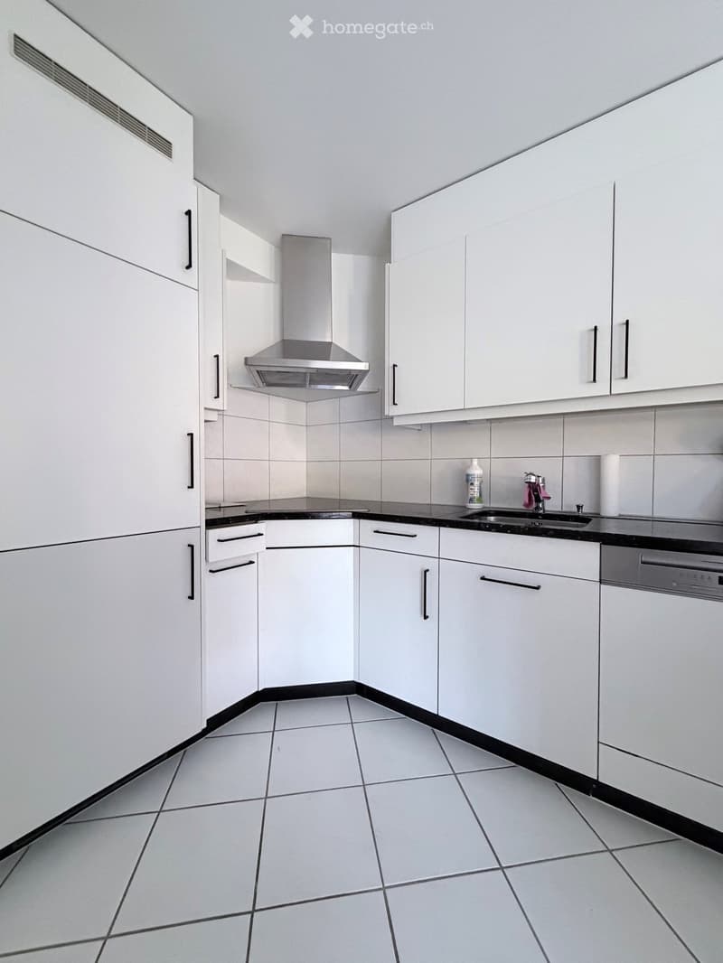 Modern kitchen with white cabinets, stainless steel sink, dishwasher, and tiled floor.