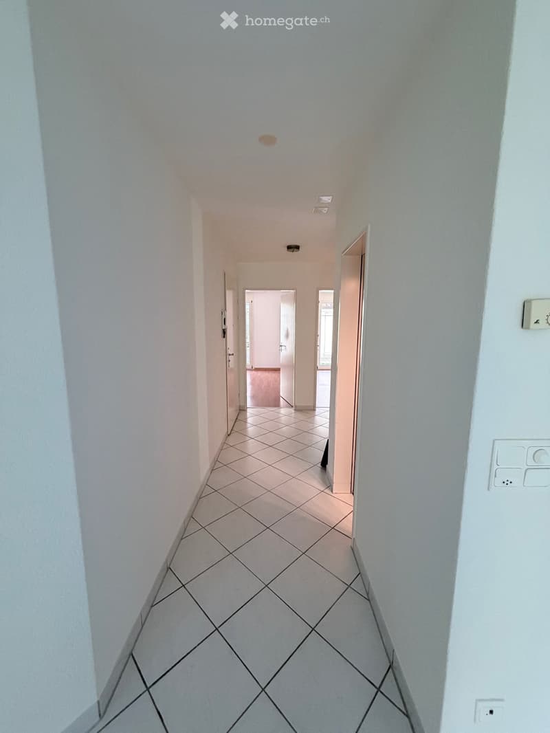 Clean, tiled hallway with white walls and multiple doors leading to other rooms.
