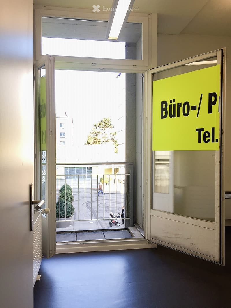 Open doorway leading to an outdoor area with a railing, visible greenery, and a sign on the right side reading "Büro-/Praxis Tel."