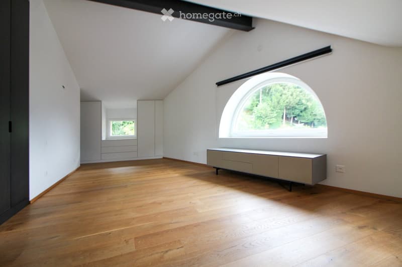 Empty room with wooden flooring, white walls, large arched window, and built-in cabinetry.