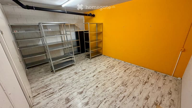 Empty room with wooden floor, yellow wall, and metal shelves.