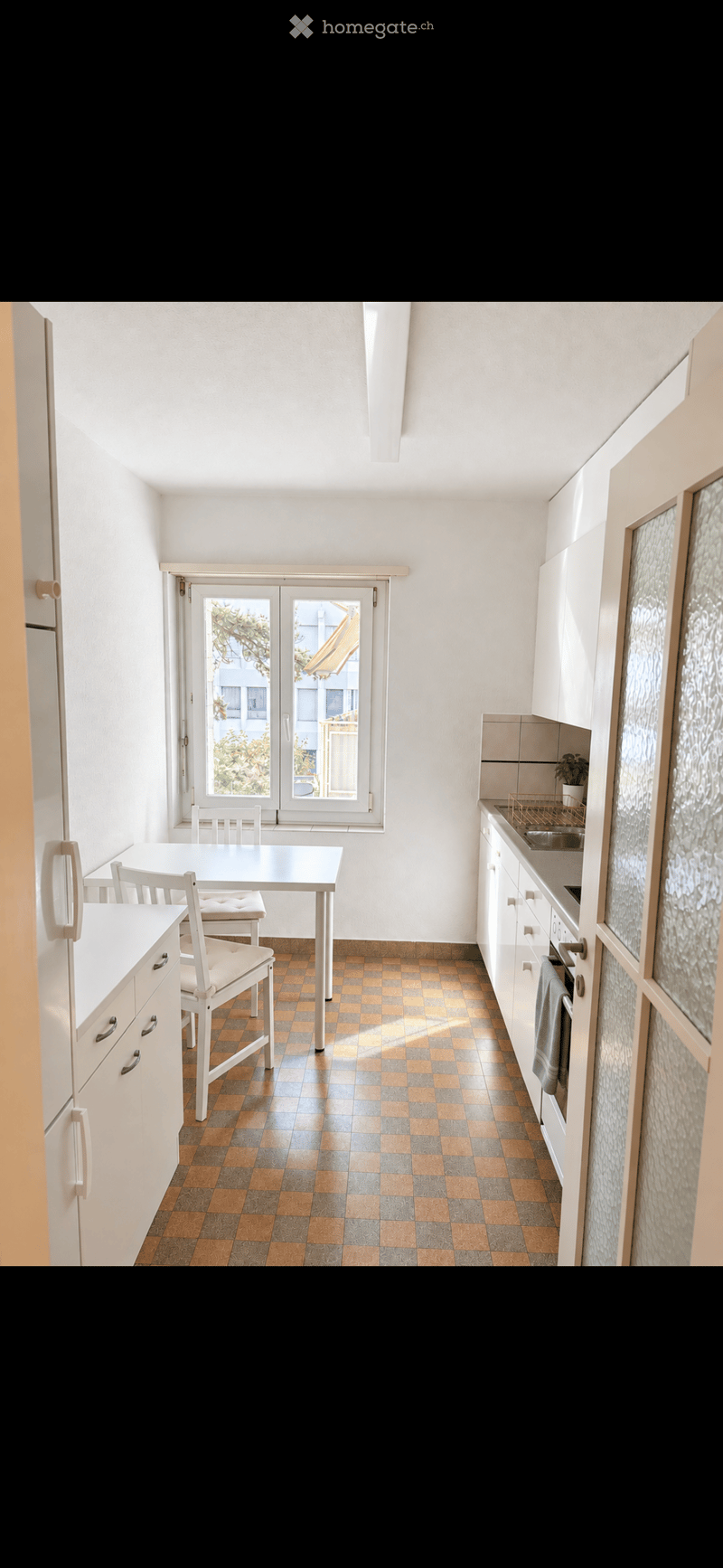 Modern kitchen with white cabinets, a dining area, and a window overlooking a balcony.
