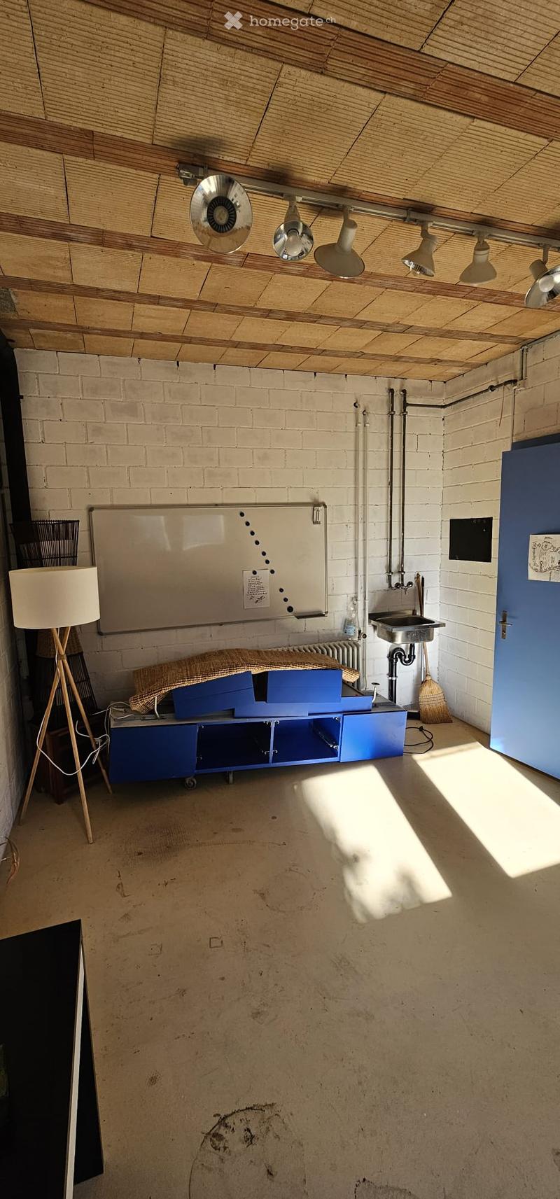 The room features exposed brick walls, a wooden ceiling, a sink, a floor lamp, a cabinet, and a radiator.
