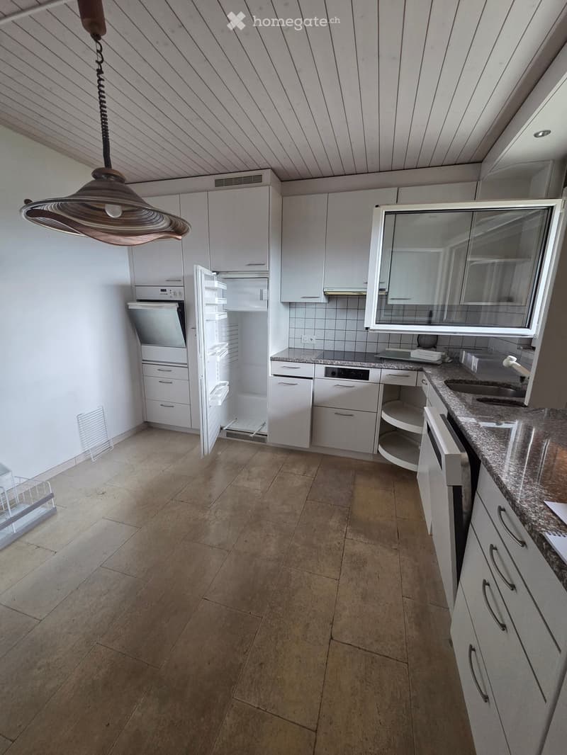 Modern kitchen with white cabinets, granite countertops, stainless steel appliances, and a pendant light fixture.